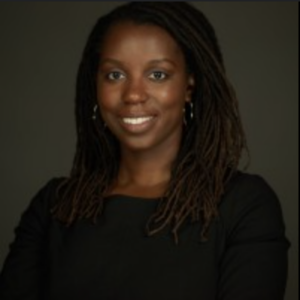 Woman with dreadlocks smiling in professional headshot, wearing black top